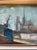 Painting depicting a charming European street scene with bare trees, buildings, and a church in the background. Soft...