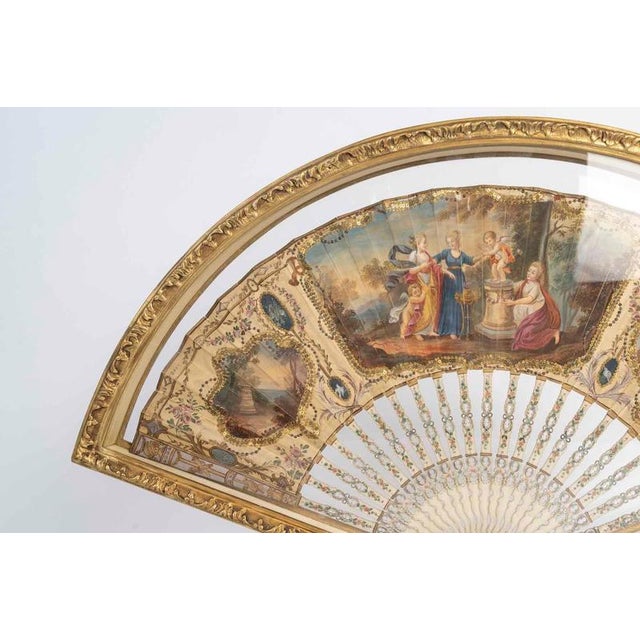 18th-century fan from the louis xvi era, displayed in its 19th-century gilded wooden stand. H: 40 cm, w: 56 cm, d: 3.5 cm