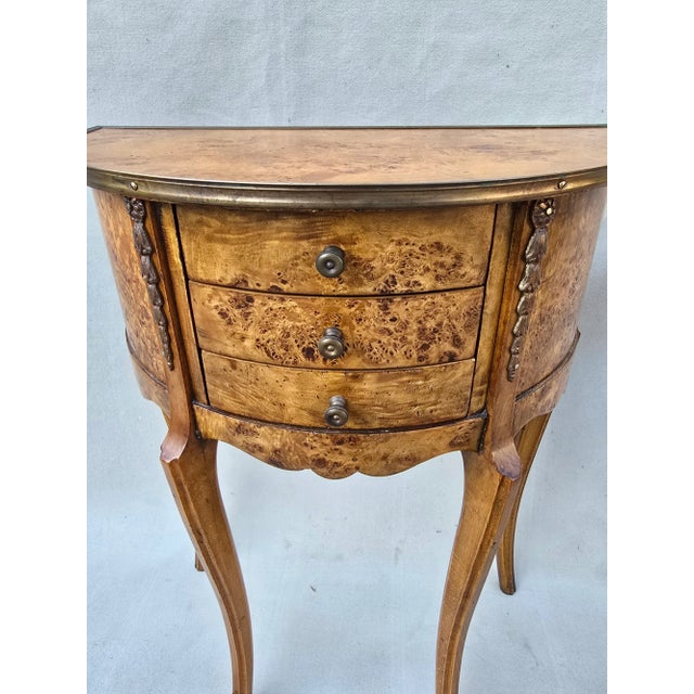 Exquisite demilune table with veneer burlwood and ormulu accents. This can be used as an accent table in a living room or...