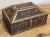 Vintage heavy wood box with brass clasp to front and rounded brass handles to each end. Features a decorative overlay of...