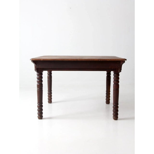 This antique wooden table adds classic charm to any kitchen. It features dark turned legs and a planked tabletop with...