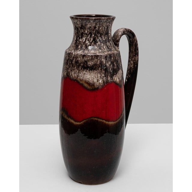 This 20th-century West German ceramic vase features the bold contrast and flowing glaze that define the iconic fat lava...