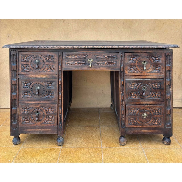 Solid and richly carved antique Spanish desk made of solid oak, dating from the early 20th century (circa 1900–1920). The...