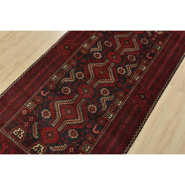 An authentic vintage tribal Baloch rug hand-knotted with fine wool and natural dyes. This rug features geometric...