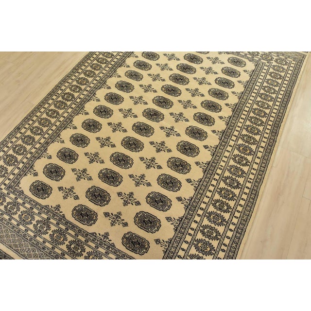 A tribal Bokhara rug hand-knotted with fine wool on a cotton foundation. This rug features rows of repeating medallions...