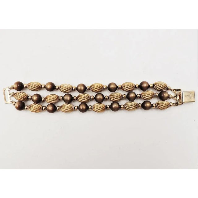 This is part of Chairish’s Costume Jewelry assortment. 1950s goldtone and brown moonglow resin beads 3-strand bracelet...