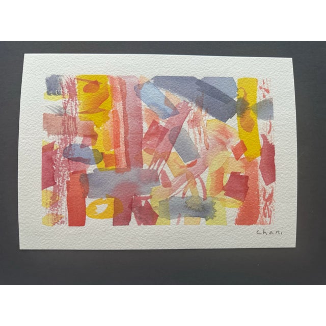 This vibrant abstract watercolor piece bursts with warm hues of red, yellow, and soft pinks, interwoven with muted blues...