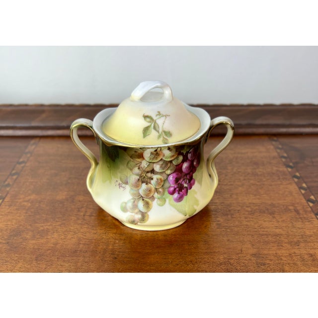 An exquisite three-piece antique Bavarian porcelain dessert or breakfast set featuring a striking, hand-painted grape and...