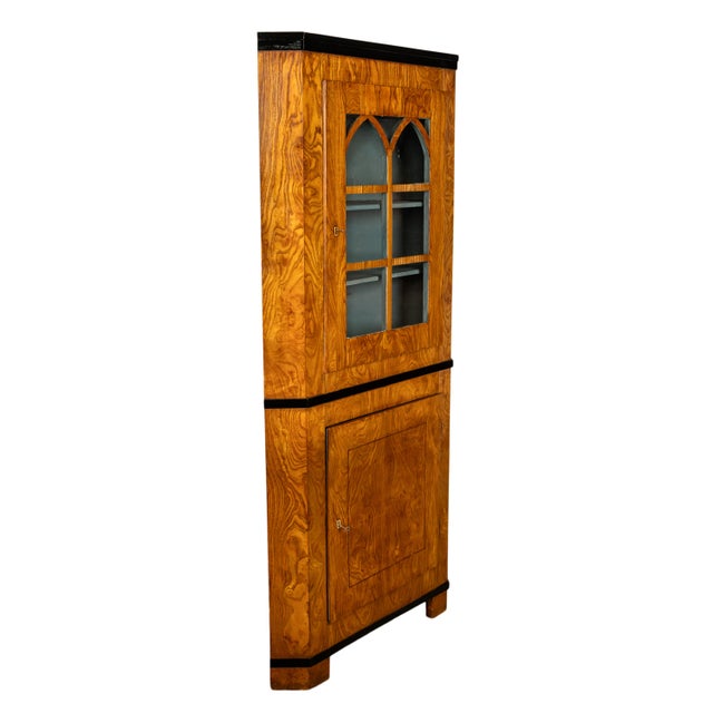 A very stylish antique Austrian Biedermeier figured ash corner cabinet, circa 1830. The cabinet with an ebonized crown and...