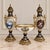 Elegant three-piece French-style porcelain garniture set featuring two matching covered vases and a coordinating central...