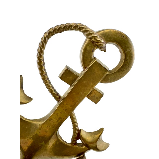 A pair of vintage solid brass anchor bookends featuring sculptural anchors with twisted rope detailing mounted atop ship's...