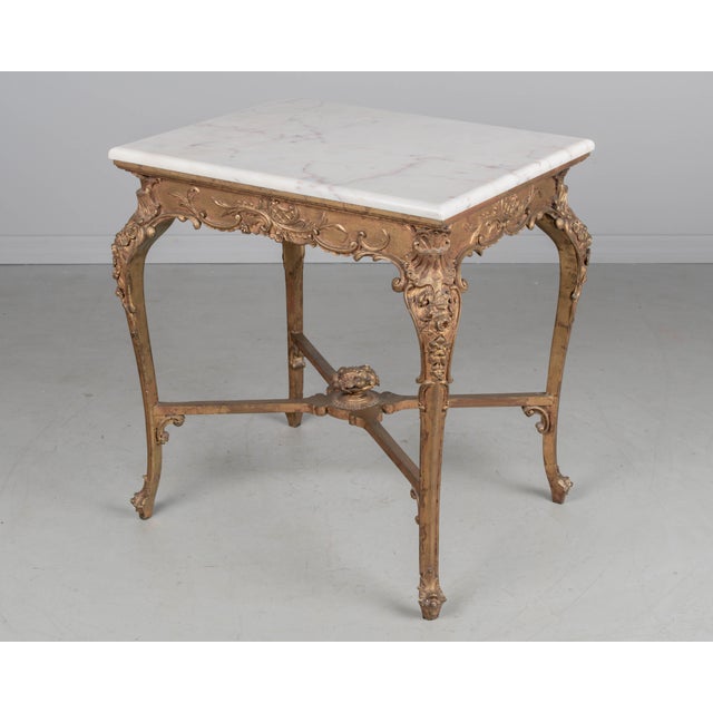 A vintage French Louis XV style center table with gilt painted patina. Sturdy cabriole legs with Rococo floral decorative...
