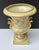 This lovely decorative ceramic urn features embossed accents, hand-painted delicate flowers, and gold griffin handles. The...