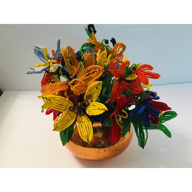 This bouquet is made up of flowers that were all hand beaded. The teapot is copper. Made in the 1970s.