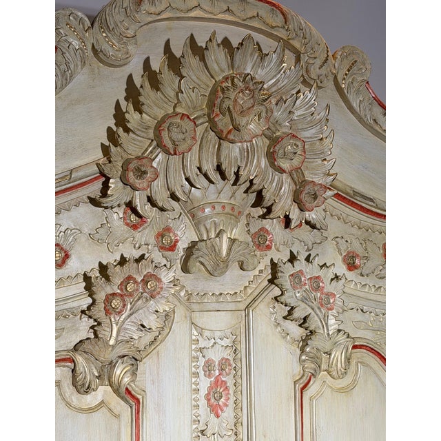 Impressive decorative armoire featuring an elaborate baroque-inspired design with richly carved floral ornamentation...
