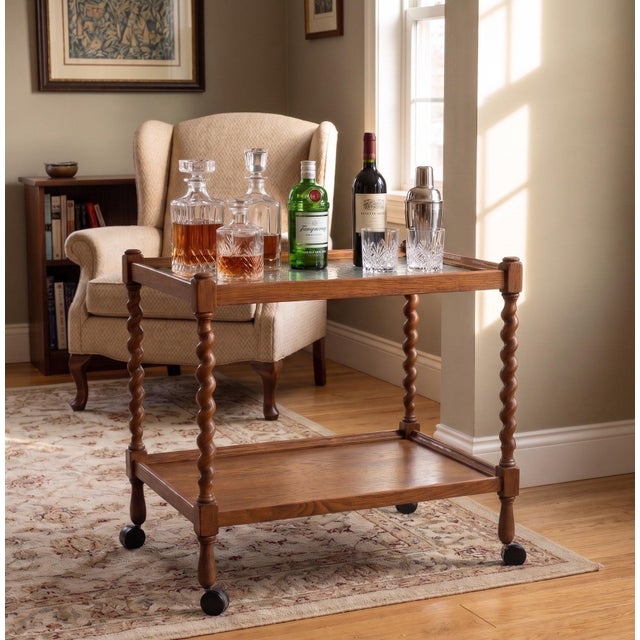Striking English tea bar cart from the 1950s in oak, featuring beautifully twisted legs and an elegant glass top. A highly...