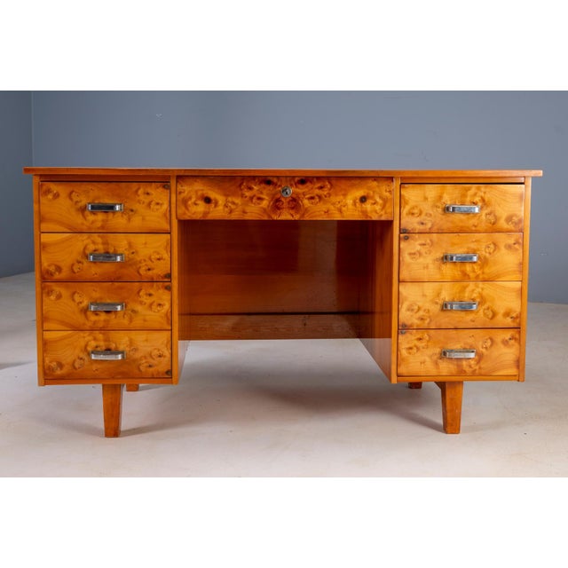 A distinctive mid-century writing desk from Czechoslovakia, featuring richly figured burl veneer, a symmetrical...