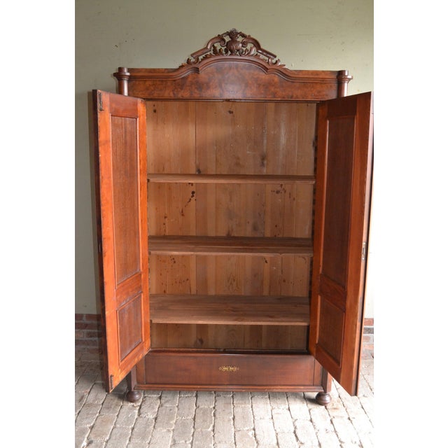 19th century German walnut wooden crested cupboard. The height is 202 cm. The depth is 120 cm. The width is 54 cm. Height-...