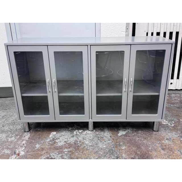 Design Plus Gallery presents a Cabinet with Glass Doors from the Late 20th Century. The cabinet is gray with a double...