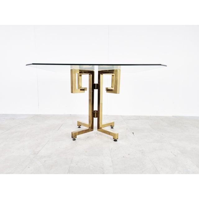 Striking geometrical brass dining table with a clear beveled glass top. Glass can be changed upon request. 1970s -...