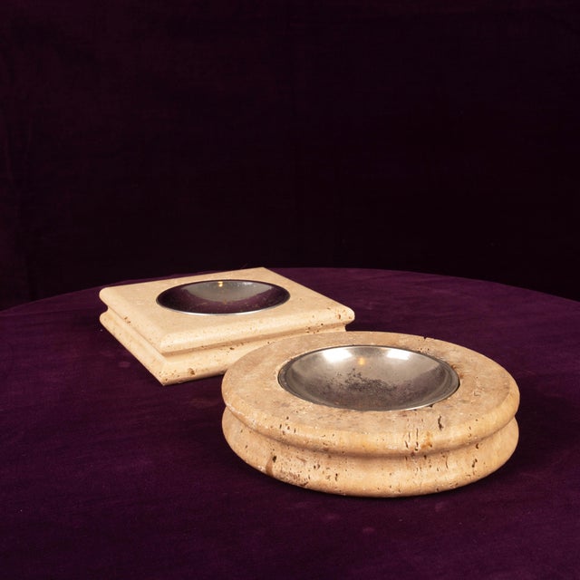 A striking pair of Italian travertine ashtrays from the 1970s — one round, one square — each fitted with a removable...