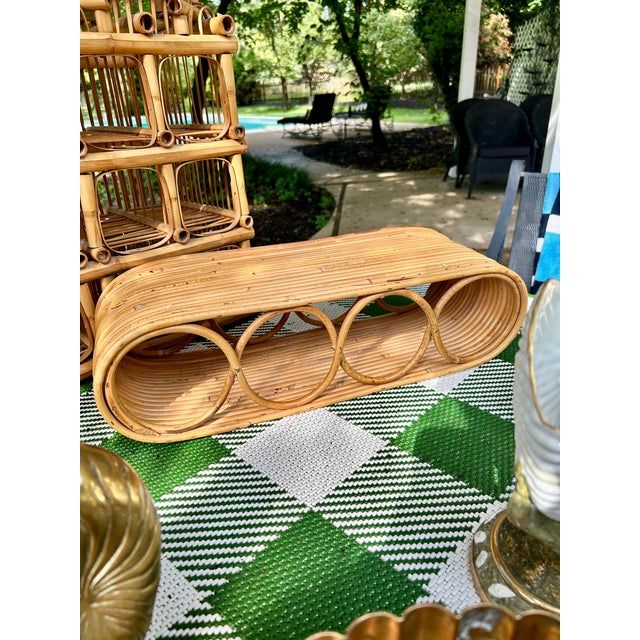 Chic vintage Italian rattan wine rack featuring a sculptural elongated form with rounded ends and a series of circular...