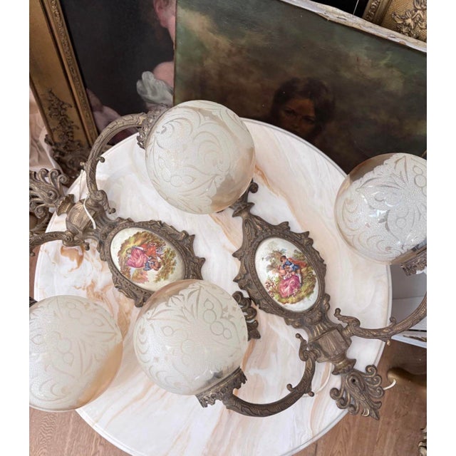 Beautiful matching pair of vintage French Rococo-style wall sconces featuring ornate scrolling metal arms, decorative...