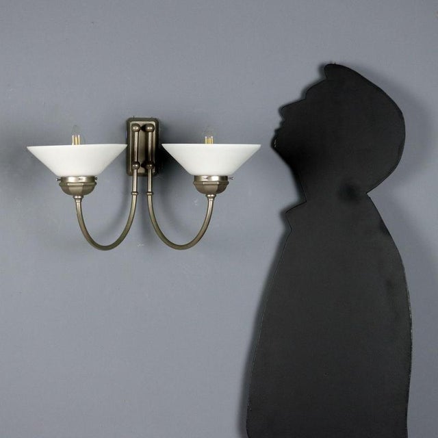 Vintage wall lamp with a metal frame and two light sources with glass diffusers. It features two E14 sockets. This piece...