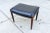 A vintage Danish modern ottoman stool in the style of Niels Moller featuring conical turned rosewood legs and a...