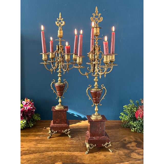 An antique pair of French candelabra offer cast bronzed metal frames in foliate form having five candle sockets raised on...