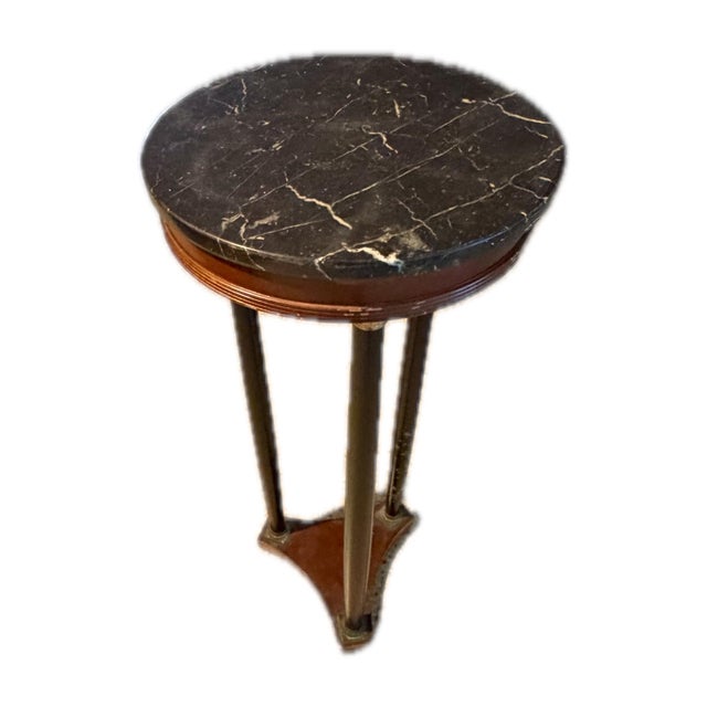 A slim, well-proportioned pedestal stand in the Neoclassical manner, topped with a dramatic black marble slab shot through...