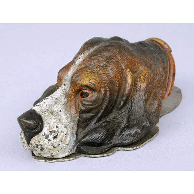 Vienna cold paint bronze letter clip in the shape of a dog's head. The head is spring hinged to a flat brass plate.
