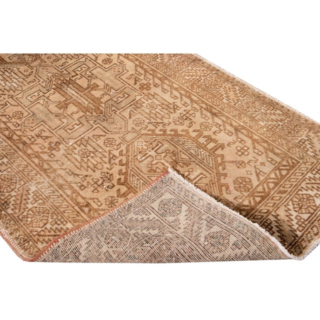 Beautiful vintage Persian Heriz hand-knotted wool runner with a beige color field. This rug has multicolor accents in an...