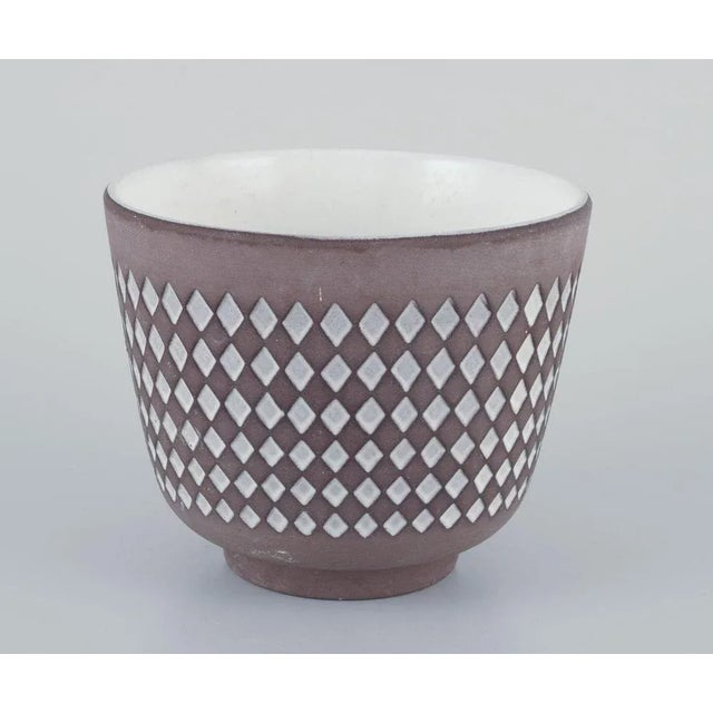 Ingrid Atterberg for Upsala Ekeby, Sweden. Two ceramic plant pots. Geometric patterns. White glaze. One pot with a hole in...