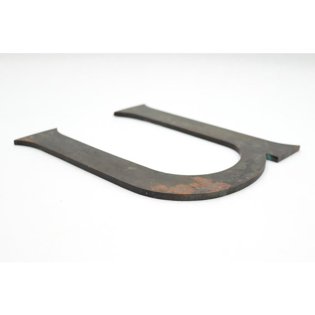 Vintage sans serif style letter U sign made of brass with an antique brass finish. The piece is flat on the back with four...