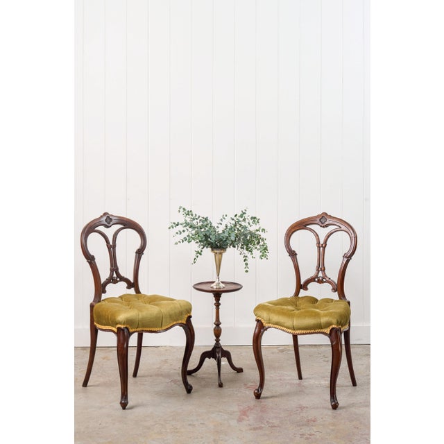 This pair of antique carved chairs features pierced balloon backs with hand-carved detailing. Each seat is cushioned and...