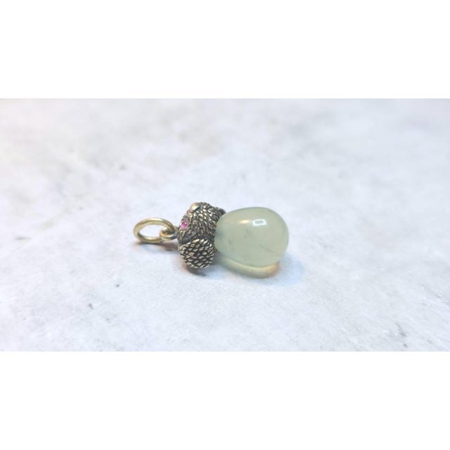 We present an adorable egg pendant in the form of a miniature carved gilt silver puppy's head with ruby eyes and a...
