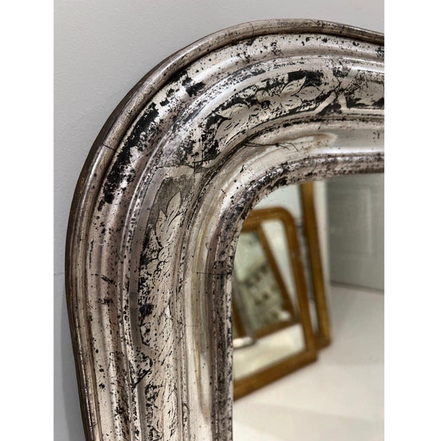 A beautiful 19th century French Louis Philippe mirror featuring a softly curved frame finished in silver leaf with a...