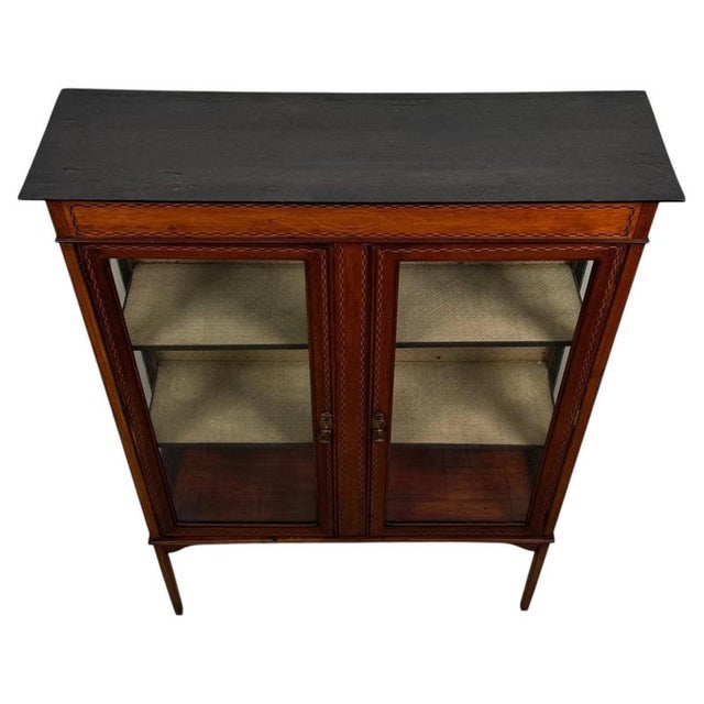 An elegant early 20th-century English display cabinet, finely crafted from mahogany and distinguished by its delicate...