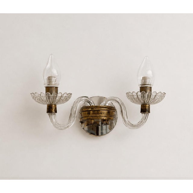 A striking pair of mid-century modern wall sconces, showcasing the exceptional artistry of Italian glassmaking. Each...
