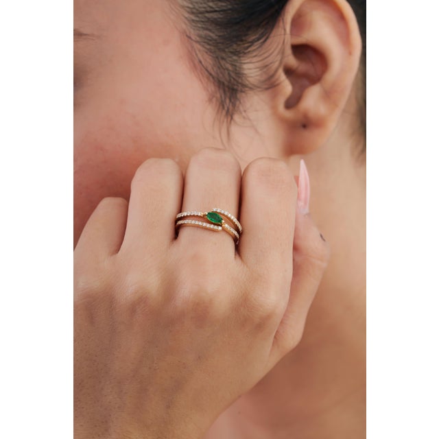 This contemporary sprial cocktail ring features a vivid green 0.20-carat emerald, set in 14K yellow gold. The marquise...