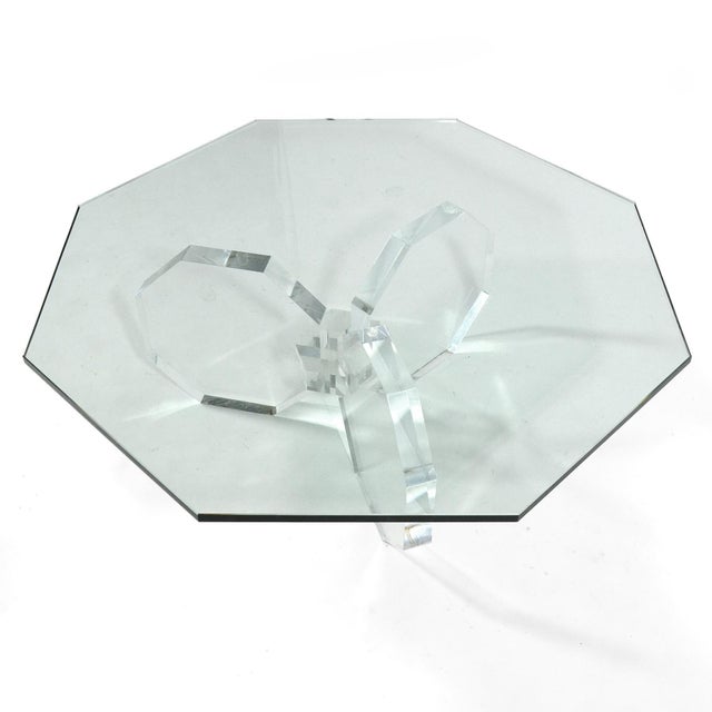 This striking coffee table has an acrylic three-legged base that echoes the octagonal shape of the glass top. Unmarked.
