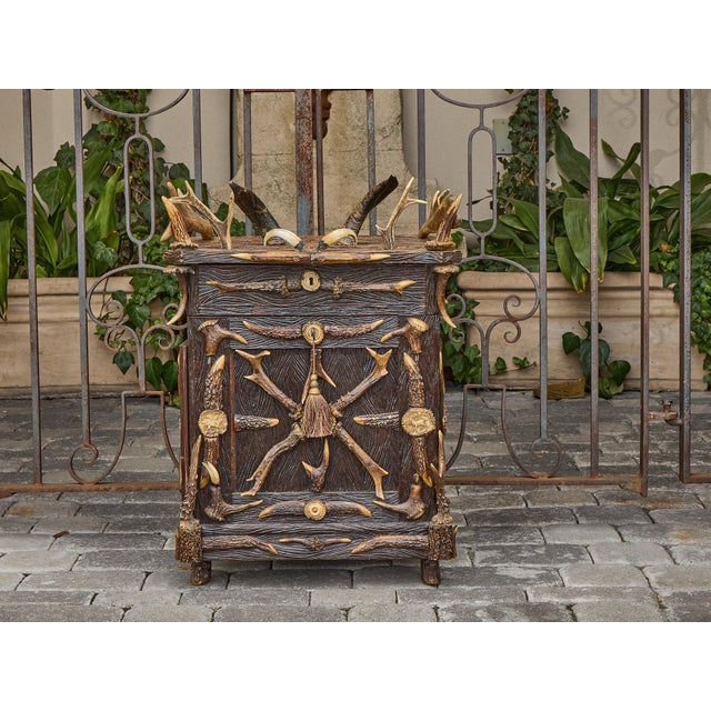 A richly textured and visually commanding Black Forest spirits cabinet, crafted in Germany around 1900. This compact yet...
