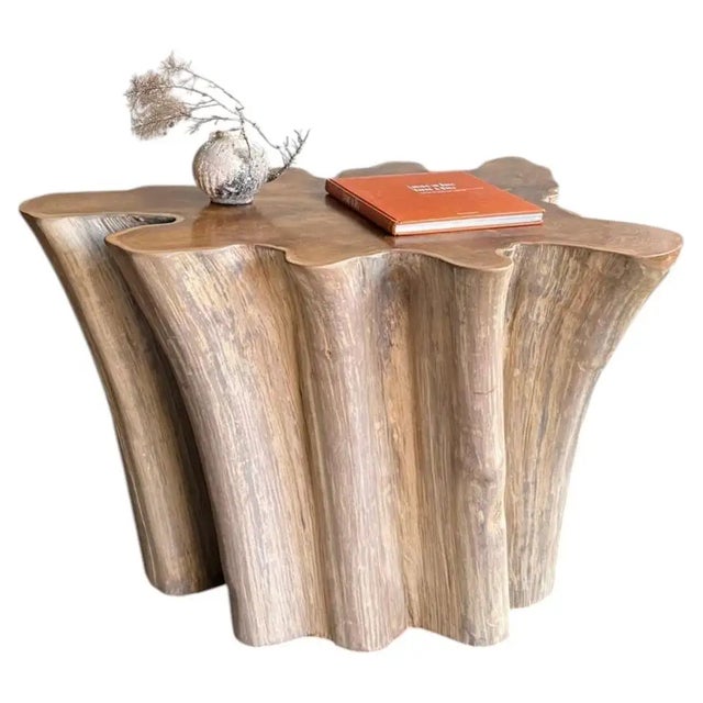A striking sculptural sofa table crafted from a substantial piece of solid teak, celebrating the raw, organic beauty of...