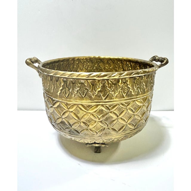 A beautifully detailed vintage brass cachepot featuring embossed patterns and classic Hollywood Regency styling. The rich...