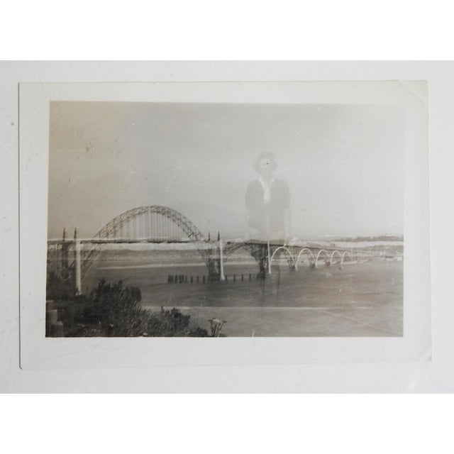 Mid 20th century double exposure snapshot photograph of Yaquina Bay Bridge in New Port, Oregon with a ghostly figure of a...
