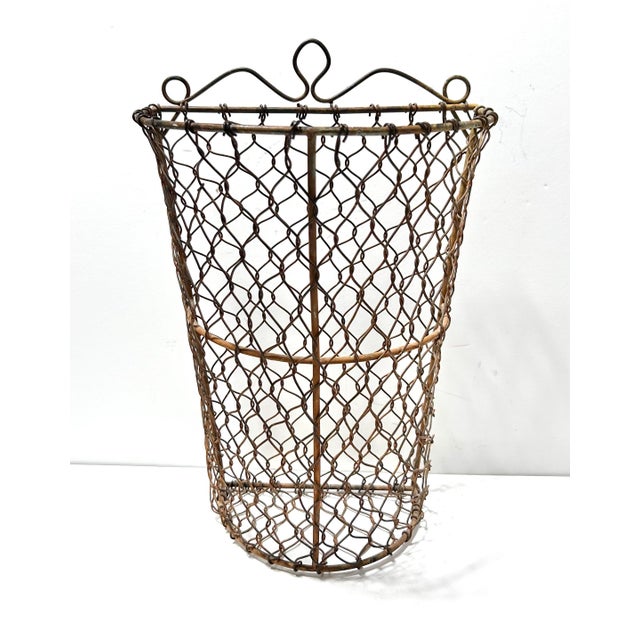 This tall antique wire basket features a beautifully hand-woven open lattice form with a sculptural, decorative rim...