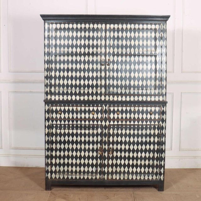 Early 19th Century English painted four door/ two drawer linen cupboard with later harlequin painted decoration. 1820 This...