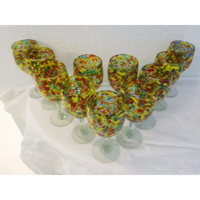 Colorful set of eleven Mexican hand blown glass goblets featuring clear bottle-glass shaded stems and vibrant, confetti...