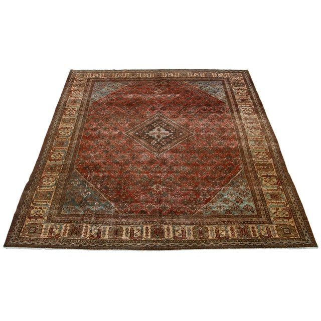 This Josheghan Persian wool rug antique hand-knotted using premium quality wool features an alluring brick red field with...